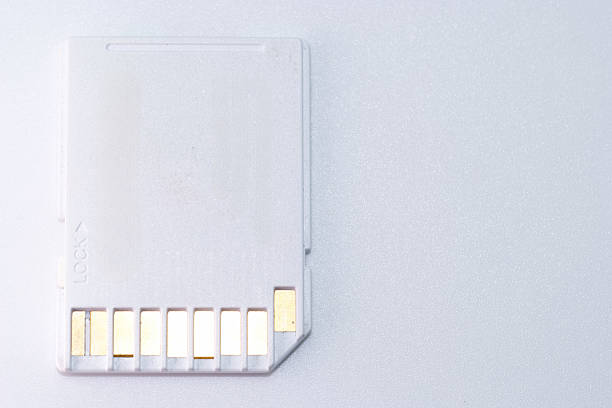 A white memory card is placed on a light surface, showcasing its gold connectors. This type of storage device is essential for transferring data in cameras, phones, and computers.