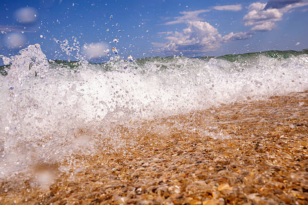 Low angle shot beneath the sea waves with small rocks, breaking waves, bottom of the sea, near the beach