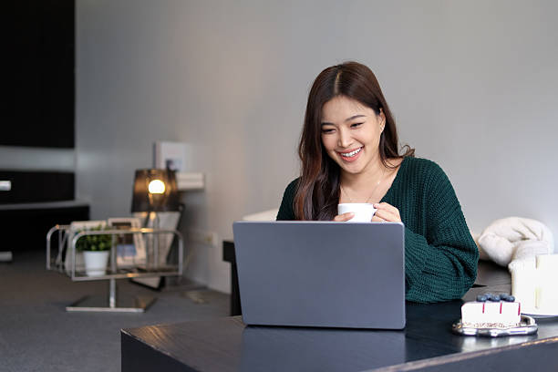 istock Young woman drinking coffee and using laptop, smiling face 2226162522