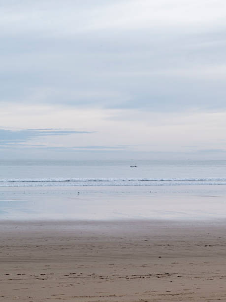 istock Small boat sailing on calm sea under cloudy sky on sandy beach 2226163728