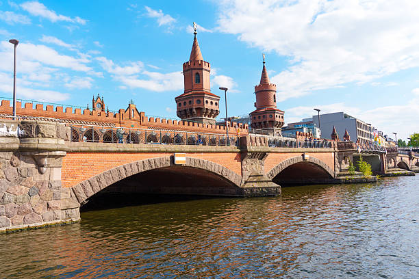 Berlin, Germany - May 30, 2025: Oberbaum Bridge features iconic brick towers and arches spanning the Spree River in Berlin, capturing a sunny day with clear blue skies and a vibrant atmosphere.