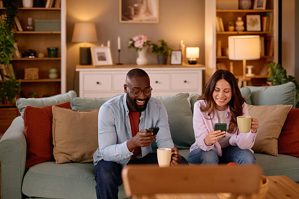 istock Happy couple using smartphones and drinking coffee on sofa at home 2226173571