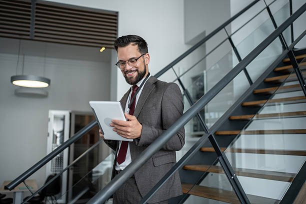 istock Smiling businessman using digital tablet on stairs in modern office 2226174086