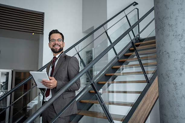 istock Smiling businessman walking downstairs holding digital tablet 2226174087