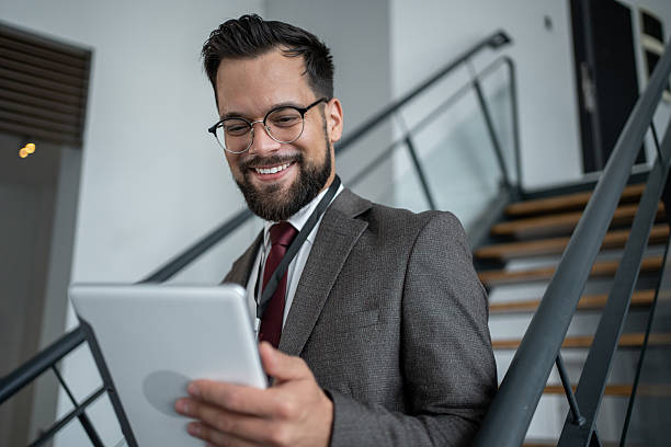 istock Smiling businessman using digital tablet on stairs in office building 2226174102