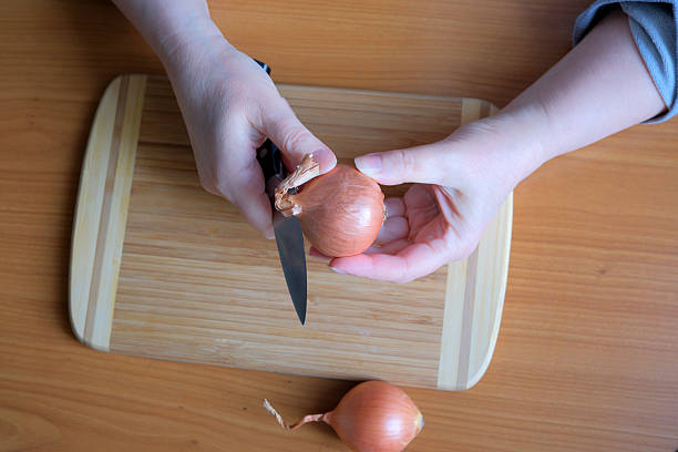 Slicing onions on a wooden cutting board at home