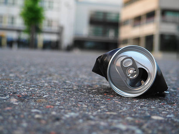 Discarded Aluminum Beverage Container Lying on the Pavement Outside a Modern Building