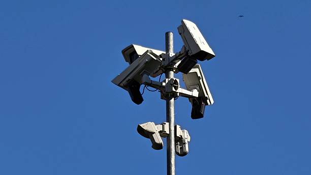 istock Surveillance cameras are positioned strategically on a tower, set against a bright, clear sky 2226178241