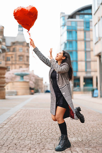 istock Joyful woman joyfully holds a heart-shaped balloon while dancing in a modern urban setting during daytime 2226179163
