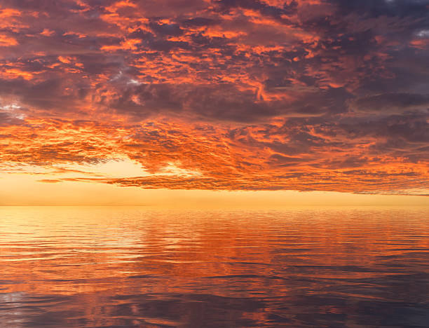 istock Dramatic sunset reflected in the smooth ripples of a lake or ocean 2226179849