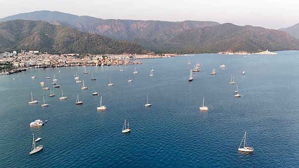 Sunset coastal city. Boats coastal town. Coastal mountain landscape, sea resort yachts, golden hour