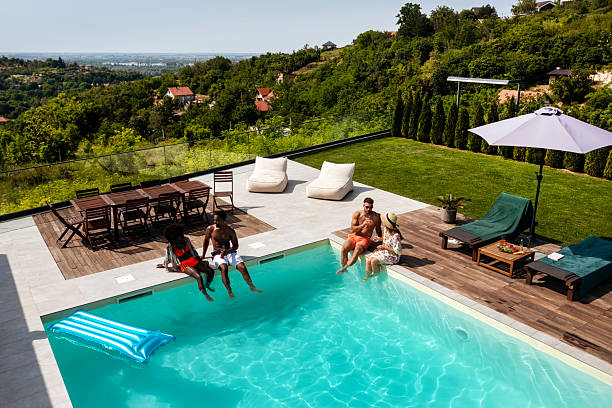 Top-down image of a residential pool with mixed race adults relaxing in clear blue water, capturing summer lifestyle and leisure.