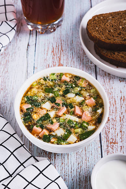 Vegetables sausage kvass soup with herbs in a bowl on the table vertical view