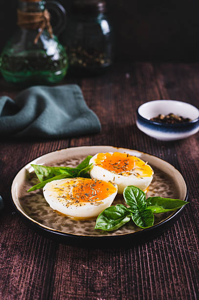 Soft-boiled egg split in half with spices and basil leaves on a plate on a table vertical view