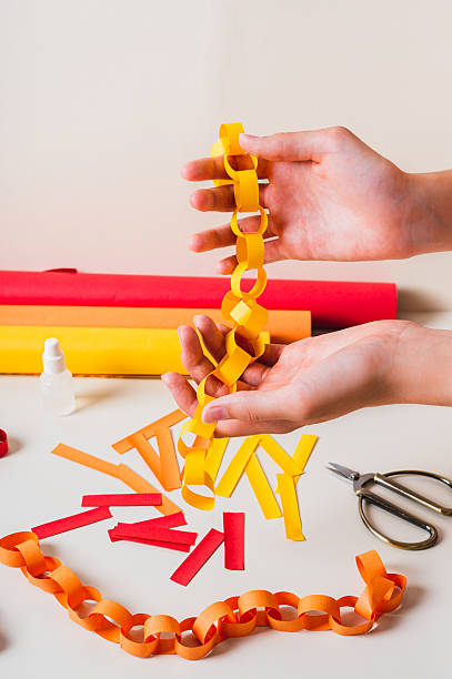 istock Handmade paper chain on women's palms and items for its production vertical view 2226188273