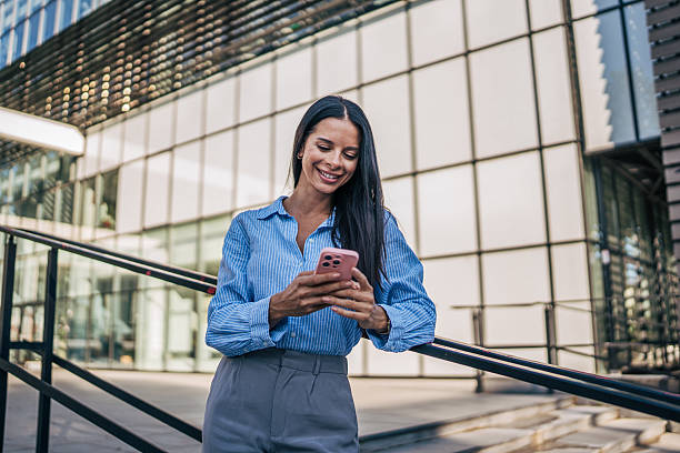 istock Smiling businesswoman using smartphone near office building 2226189217