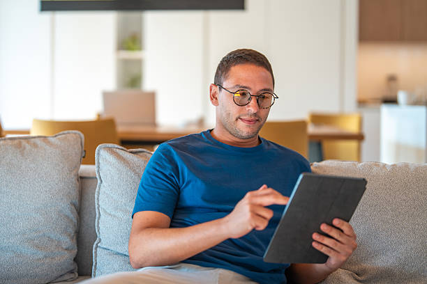 istock Hispanic Businessman in Blue Shirt Working on Tablet in Modern Home Setting 2226189260