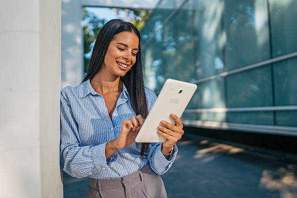 istock Smiling businesswoman using digital tablet in front of office building 2226189481