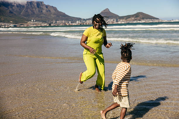 Parent and kid laugh as they run from the waves rolling onto shore.