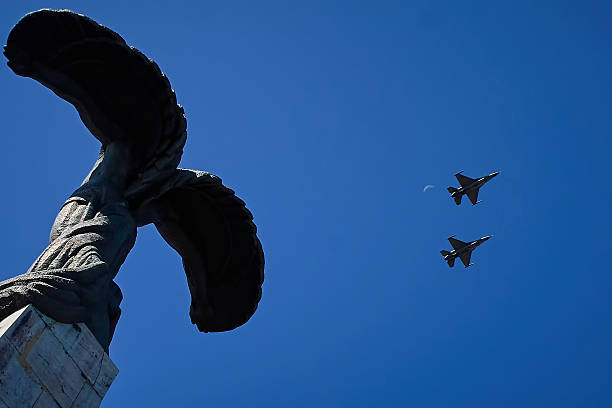 Two military jets fly through burnt cloudy skies with the sun in the background