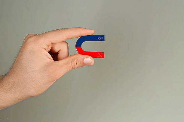 istock Man holding horseshoe magnet on grey background, closeup. Space for text 2226193560