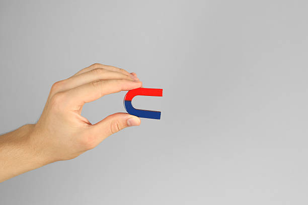 istock Man holding horseshoe magnet on grey background, closeup. Space for text 2226193608