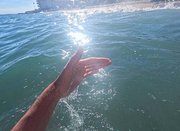 Tourist enjoying refreshing ocean water during summer vacation, creating sparkling droplets and capturing user-generated content at the beach