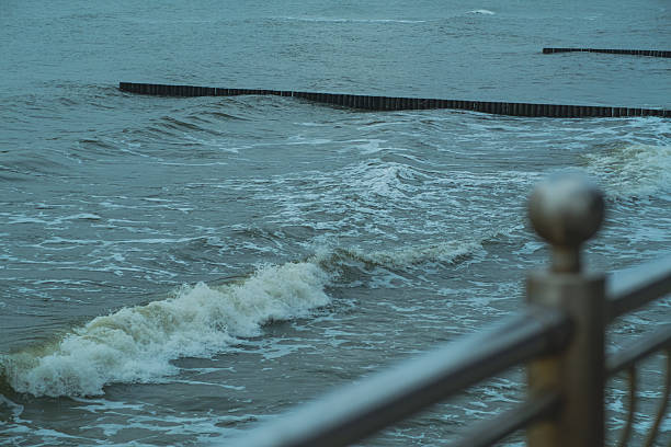 istock Waves Gently Lapping Against an Expansive Breakwater During a Cloudy Day at the Coastline 2226198026