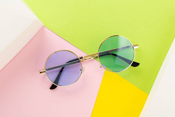 Blue sunglasses on color background, top view