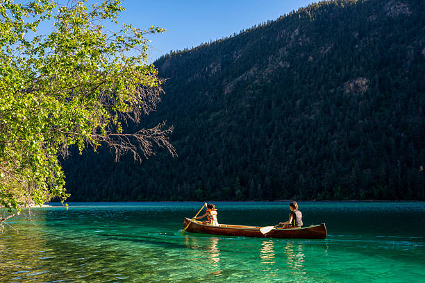 Young girls paddle canoe on turquoise mountain lake, Whistler, British Columbia