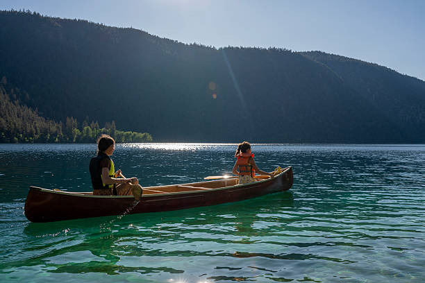 istock Young girls paddle canoe on tranquil mountain lake 2226205312