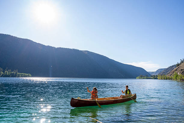 istock Young girls paddle canoe on tranquil mountain lake 2226205643