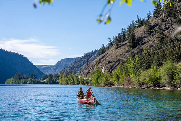 istock Young girls paddle canoe on tranquil mountain lake 2226206170