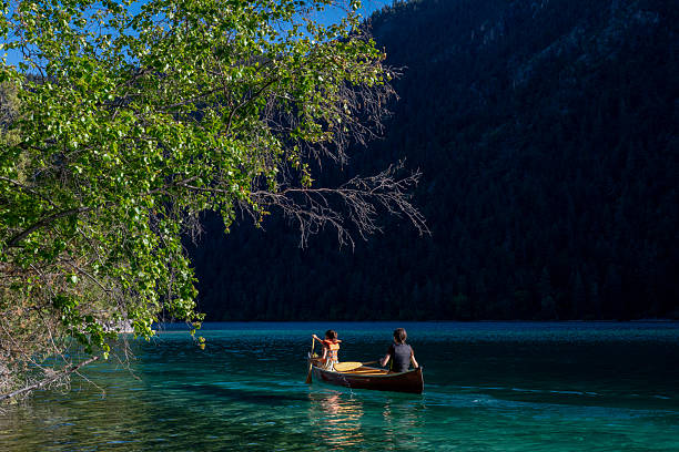 Young girls paddle canoe on turquoise mountain lake, Whistler, British Columbia