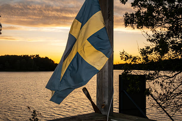 Stockholm, Sweden A Swedish flag on a porch blows in the wind over Lake Malaren at sunset.