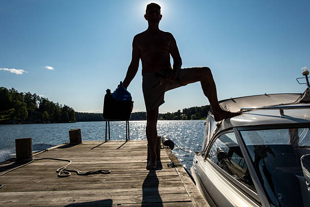 Young child stepping into the lake from a wooden pier, enjoying summer in Finland.