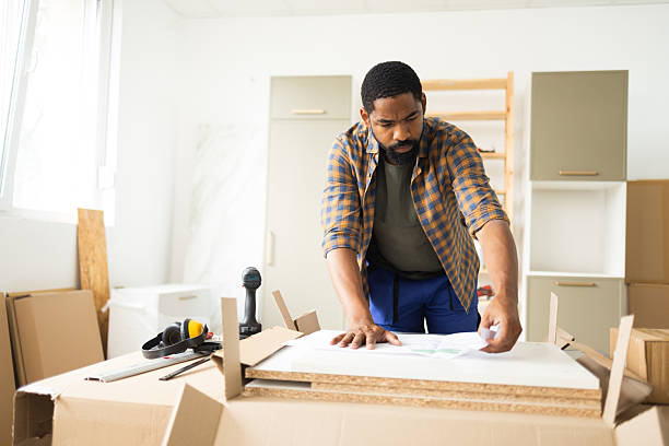istock Carpenter assembling furniture using instructions in apartment 2226217416