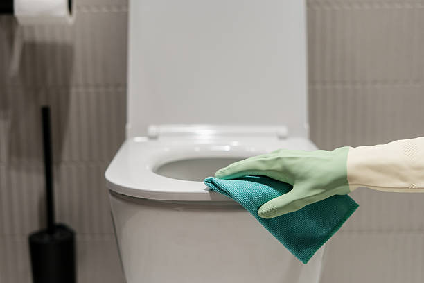 Cleaning a white toilet bowl in a modern bathroom environment
