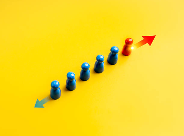 istock Different ways, difference, unique, business solution concept. The brave red one peg doll moving opposite of other blues, with arrow direction signs, on yellow background. Stand out from the crowd. 2226225250