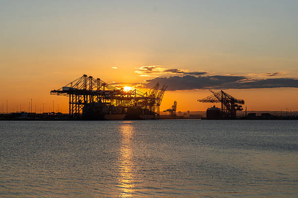 Evening view of Vancouver port dock with illuminated light post and cranes in the background.