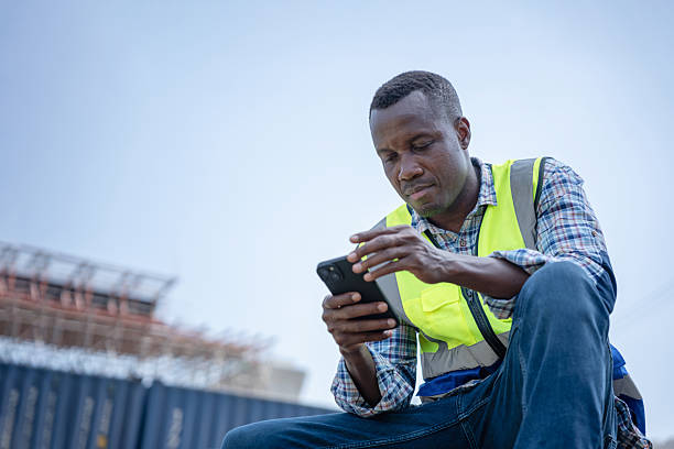 istock Construction Worker Using Smartphone on Job Site, Engineer in Safety Vest Checking Phone at Work, Industrial Professional Texting or Browse on Mobile Device 2226233720
