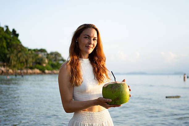 Tourist enjoying a refreshing coconut water on a tropical beach