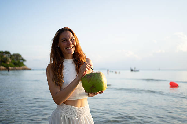 istock Young woman drinking coconut water on a tropical beach 2226240666