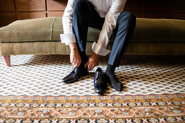 istock Groom preparing for wedding by putting on shoes in elegant setting 2226241100