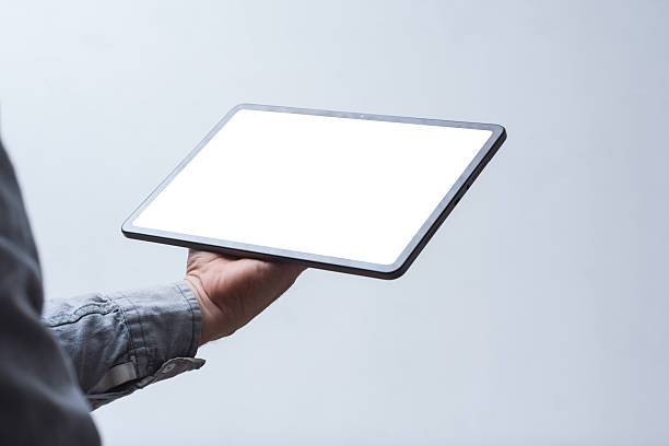 Close-up of a tablet with a blank white screen held in a man's hand against a neutral background. Mockup for showcasing web design, mobile apps, UI UX concepts and digital content.