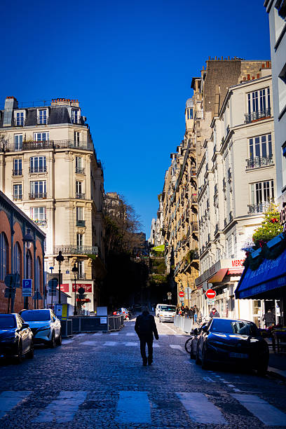 Photograph of a man walking down the street in Montmartre, Paris, France. This photograph was taken on a sunny winter day in January 2025.