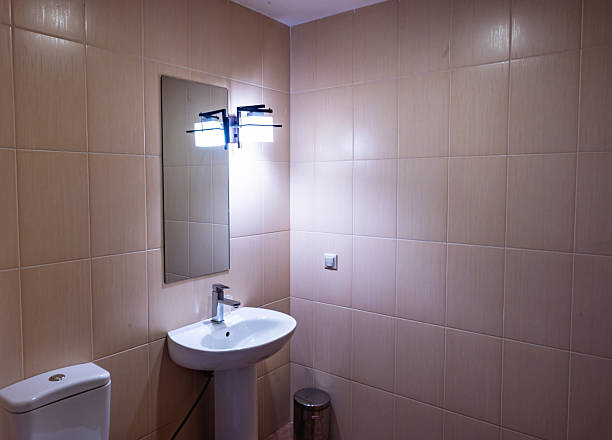 Modern bathroom setting with a white pedestal sink, large wall mirror, and contemporary light fixture. The arrangement highlights clean lines and functional design.