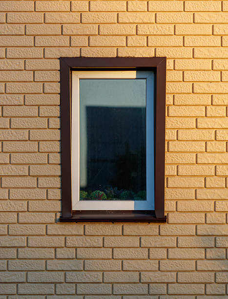A window with a view of a brick wall. The window is rectangular and has a white frame
