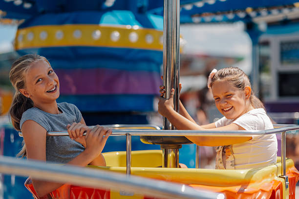 istock Two smiling girls having fun on a carnival ride 2226248490