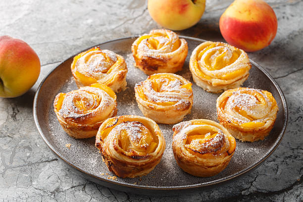 Fresh puff pastry peach mini tarts muffins close-up on plate on table. horizontal
